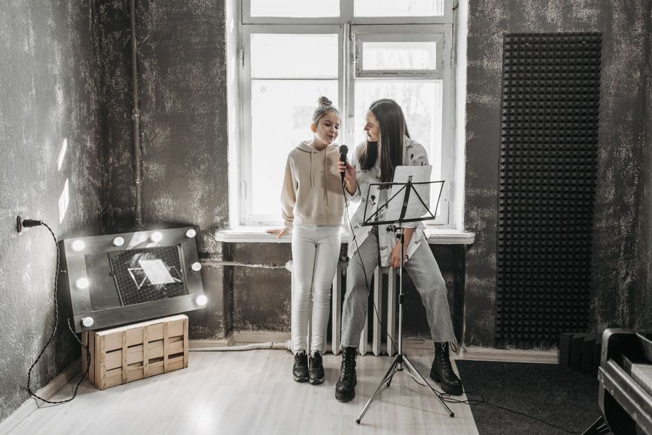 A teenager and teacher singing in a modern studio, enhancing vocal skills.