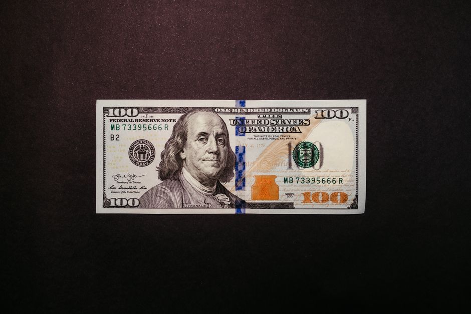 Close-up of a US 100 dollar bill displayed on a black background.